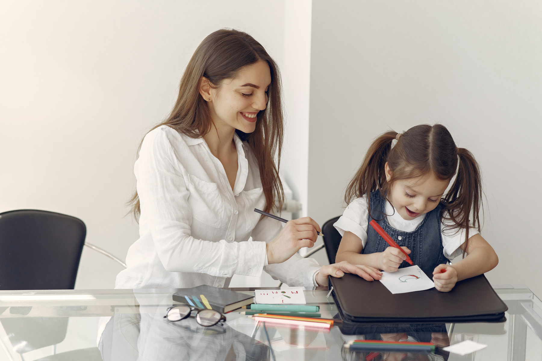 Young woman tutoring little girl in office