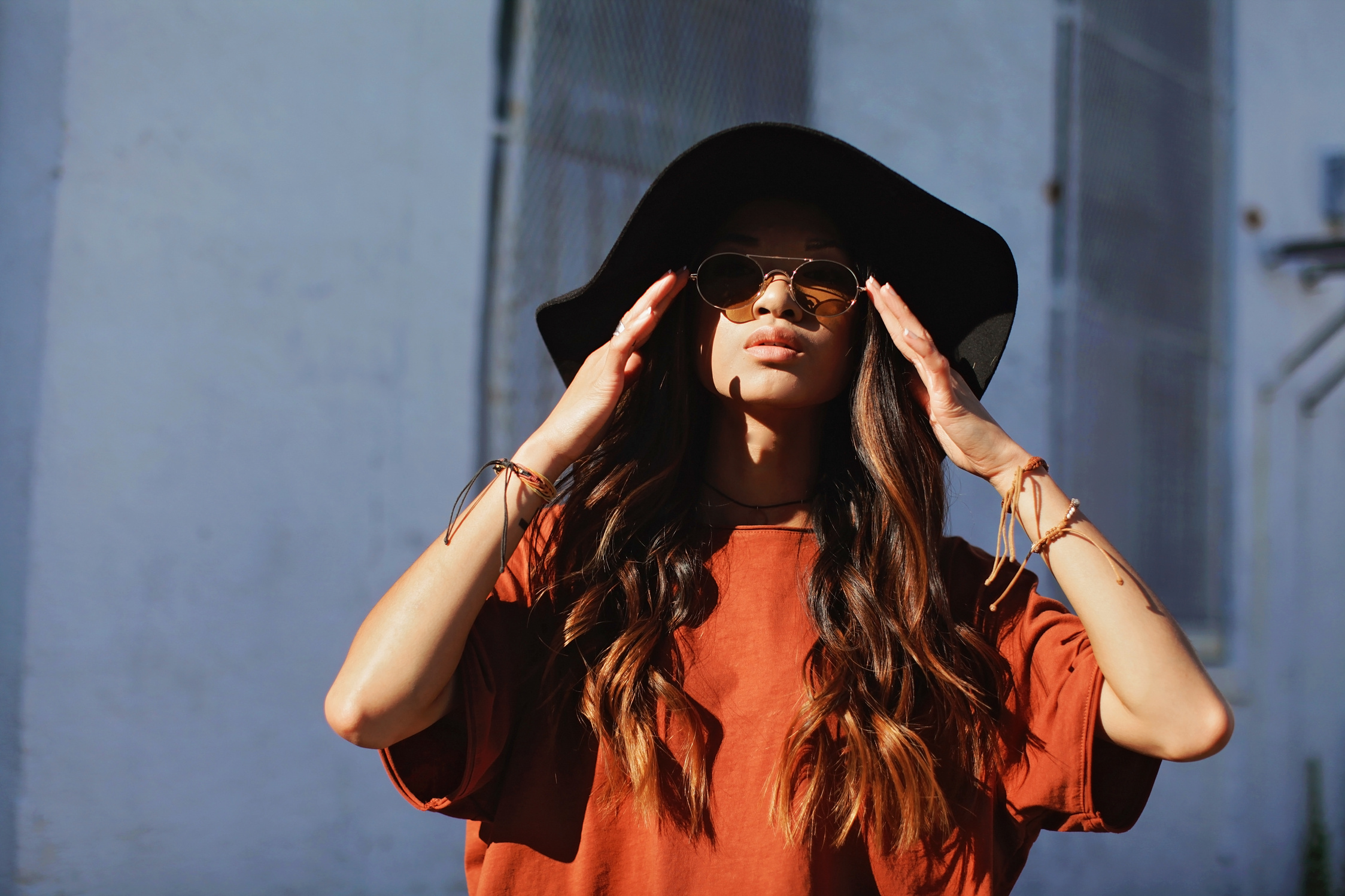 Woman Wearing Brown Shirt and Sun hat Beside White Wall