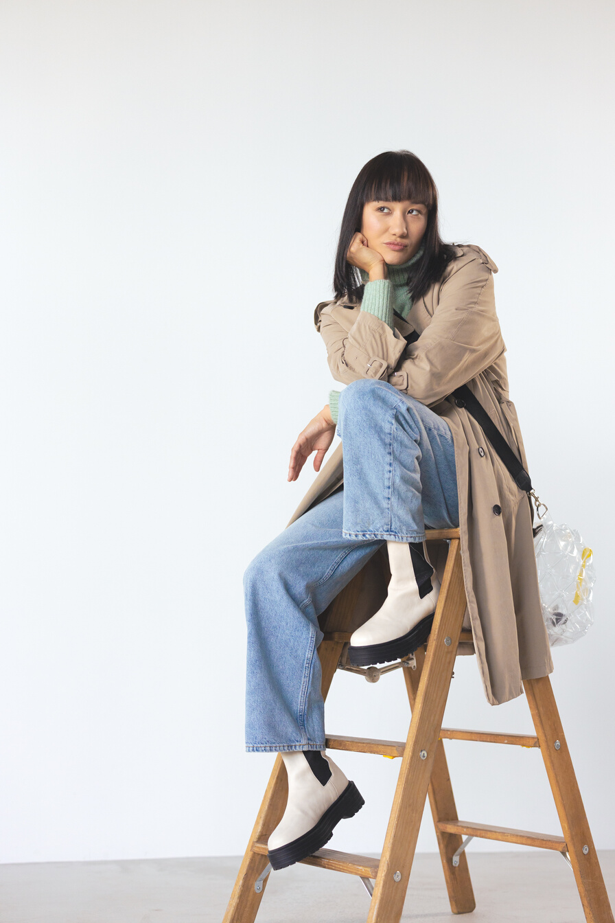 Woman in Brown Trench Coat Sitting on Brown Wooden Ladder